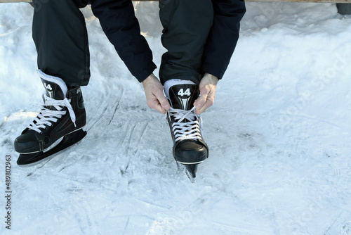 Man ties his shoelaces on hockey skates on an ice skating rink. Hockey equipment.