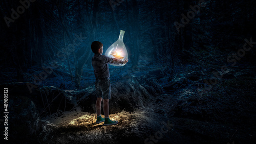 Boy holding glass flask with landscape inside it