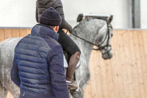 Canvas Print A riding instructor give lessons to an equestrian on a horse in a riding hall