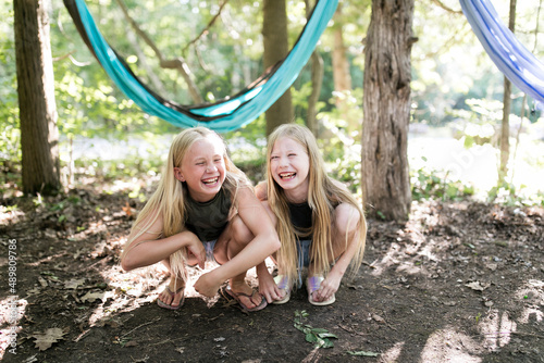 Happy girls crouching in front of hammock in forest photo