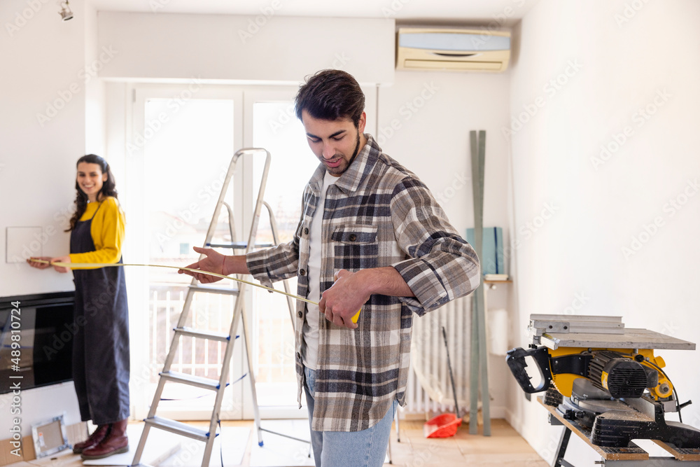Young couple measuring room at home renovation work Young couple measuring room at home renovation work