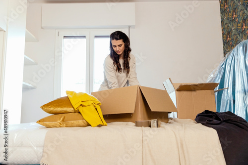 Young woman unpacking carboard boxes and relocating in new house photo