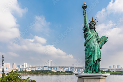 Japan, Kanto Region, Tokyo, Replica of Statue of Liberty standing against clouds with Sumida River and Rainbow Bridge in background