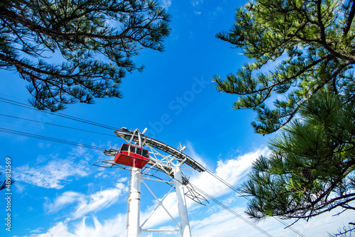 Cable car or gondola lift passing by on top of the mountain on beautiful sunny day with blue sky