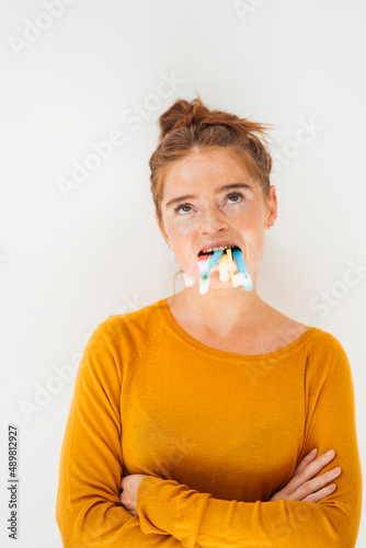 Woman holding toothbrushes in mouth at studio photo