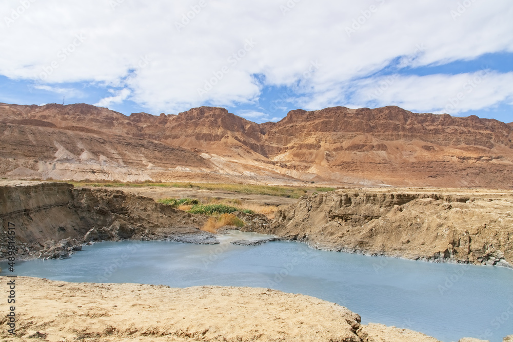 Sinkhole filled with turquoise water, near Dead Sea coastline. Hole formed when underground salt is dissolved by freshwater intrusion, due to continuing sea-level drop. . High quality photo