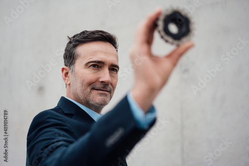 Businessman holding and looking at gear photo