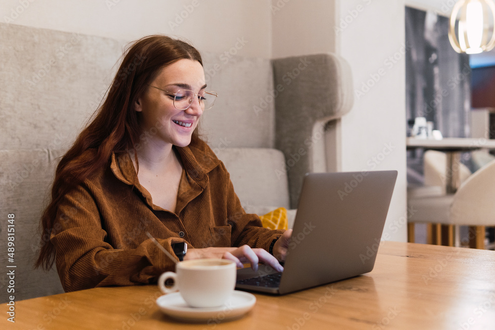 Smiling businesswoman working on laptop in coffee shop Smiling businesswoman working on laptop in coffee shop