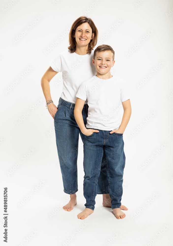 Smiling mother and son standing with hands in pockets against white background Smiling mother and son standing with hands in pockets against white background