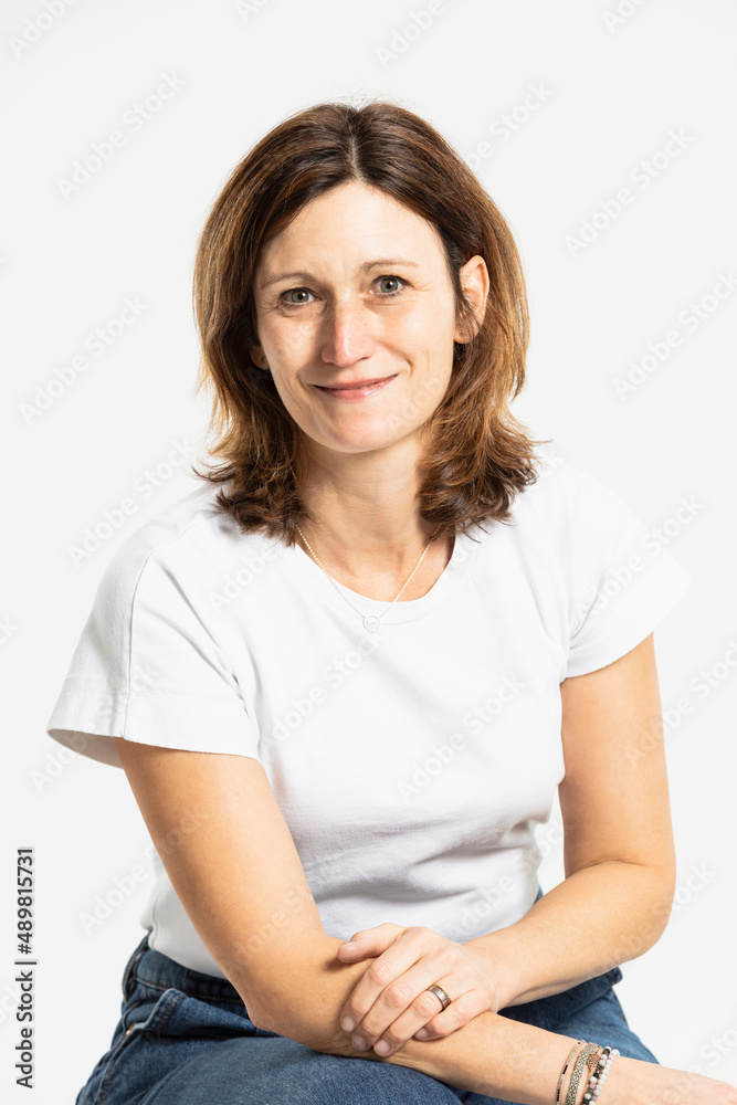 Smiling woman sitting against white background in studio Smiling woman sitting against white background in studio