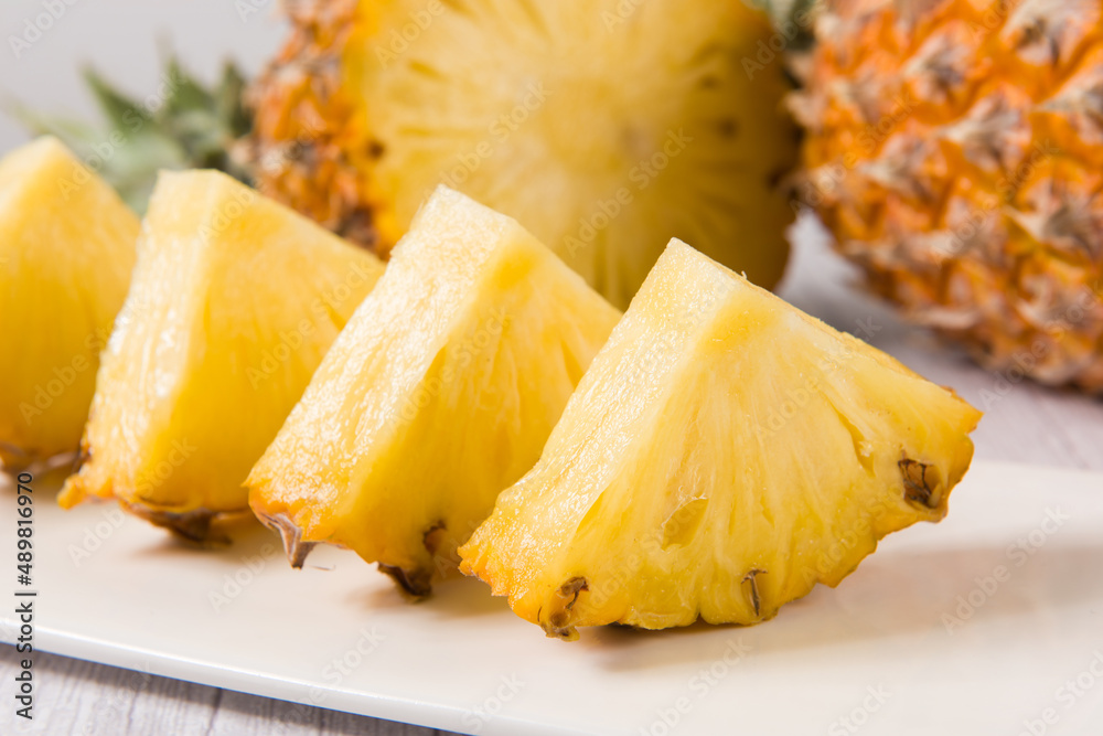 fresh pineapple (Ananas comosus) with slices on wooden table fresh pineapple (Ananas comosus) with slices on wooden table