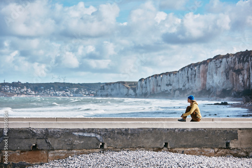 Woman sitting on wall by sea at vacation