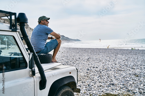 Tourist sitting on car at beach
