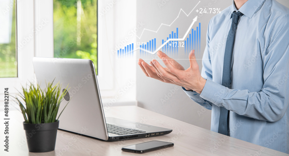 Business man holding tablet and showing holographic graphs and stock market statistics gain profits. Concept of growth planning and business strategy. Display of good economy form digital screen.