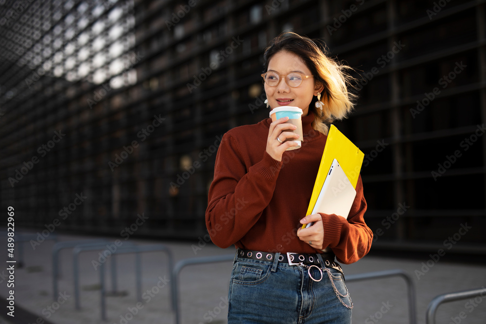 Fototapeta premium Beautiful Chinese woman enjoy in fresh coffee. Young fashion woman holding coffee cup while walking aroung the city.