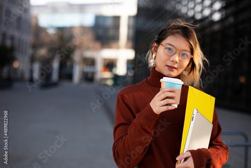 Beautiful Chinese woman enjoy in fresh coffee. Young fashion woman holding coffee cup while walking aroung the city.