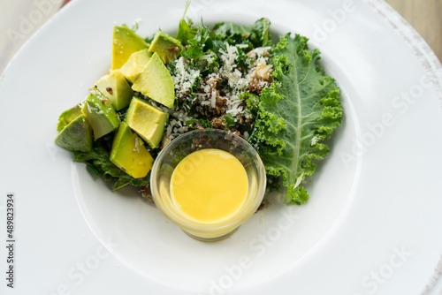 Avocado and Curl leaf kale with lettuce vegetable and Salad dressing that healthy food in white plate at restaurant. photo