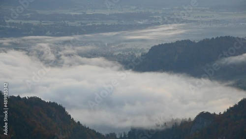 Time lapse, elevated or aerial view of fog moving above lake Bled, Slovenia. Cloud inversion. Fog or mist in alpine valley. Static shot