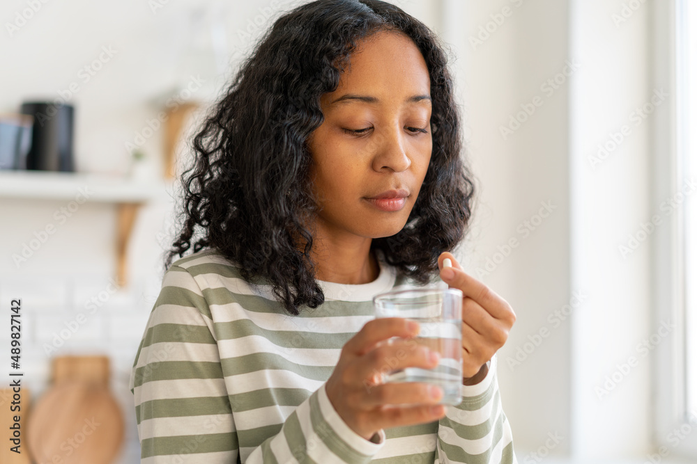 African-american female washing down pill with glass of water.Healthy supplement remedy treatment African-american female washing down pill with glass of water.Healthy supplement remedy treatment