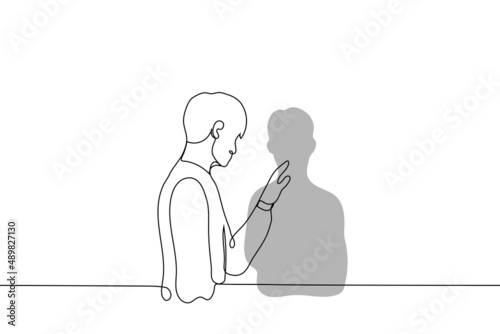 man stands near the wall and touches his shadow - one line drawing vector. the concept of self-reflection, self-knowledge,  looking at yourself