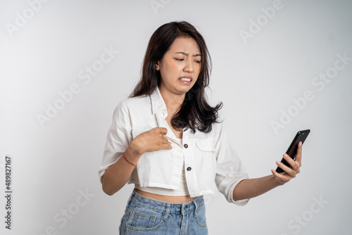 woman feel disgusted and shocked while looking at her mobile phone
