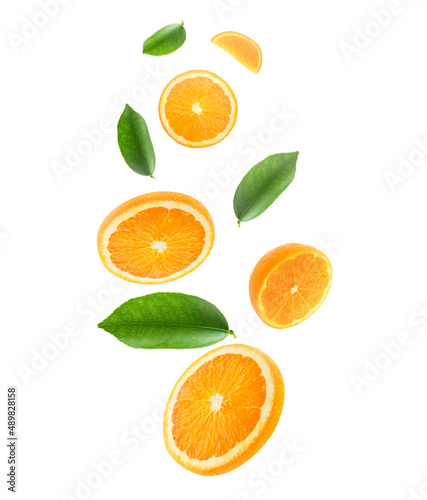 Falling juicy oranges with green leaves isolated on transparent background. Flying defocusing slices of oranges. Applicable for fruit juice advertising