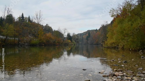 Calm river flowing in pristine alpine valley. Colorful shore in autumn or fall season. Amazing nature in Slovenia. Ecology and clean environment concept. Static shot, real time
