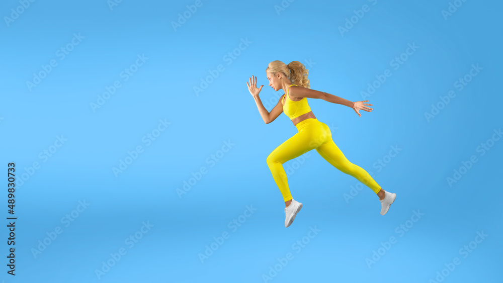 Serious woman running at blue studio background