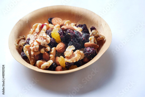 Mix fruit and nut mix in a small wooden cup on a white background. Healthy choice for energy. Raisins, walnut, almond in a bowl. Nature product