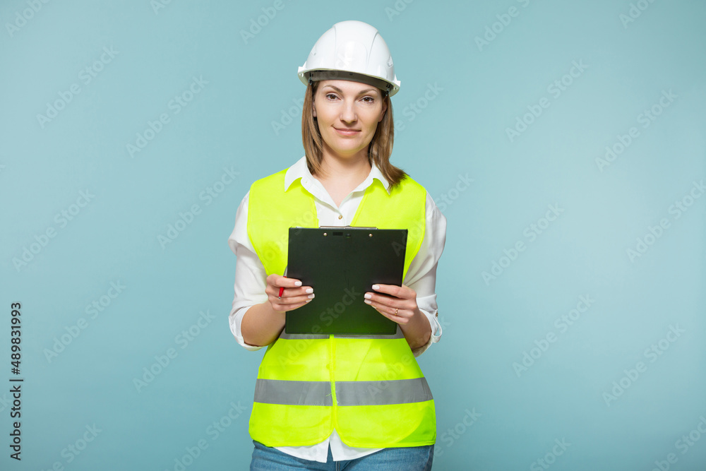 Professional engineer. A woman in a hardhat and bright jelly is using a tablet, on a blue background. Copy paste. Professional engineer. A woman in a hardhat and bright jelly is using a tablet, on a blue background. Copy paste.