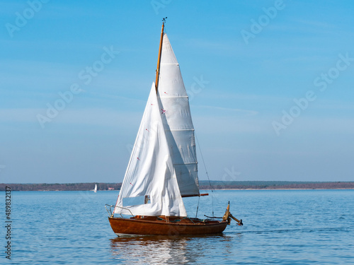 Wooden sailboat sails on a beautiful spring day