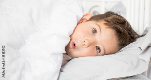 Portrait of playful little boy in bed. Daily regime concept