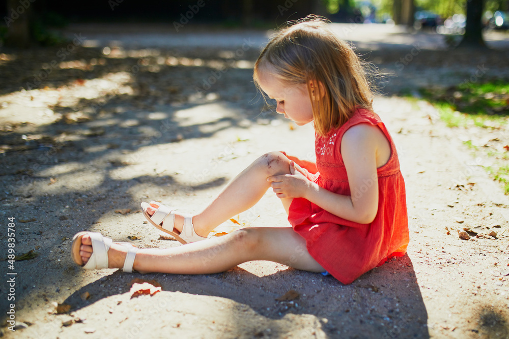 Cute little girl sitting on the ground after falling down Stock Photo