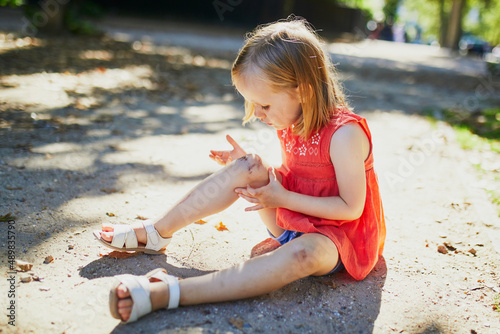 Cute little girl sitting on the ground after falling down