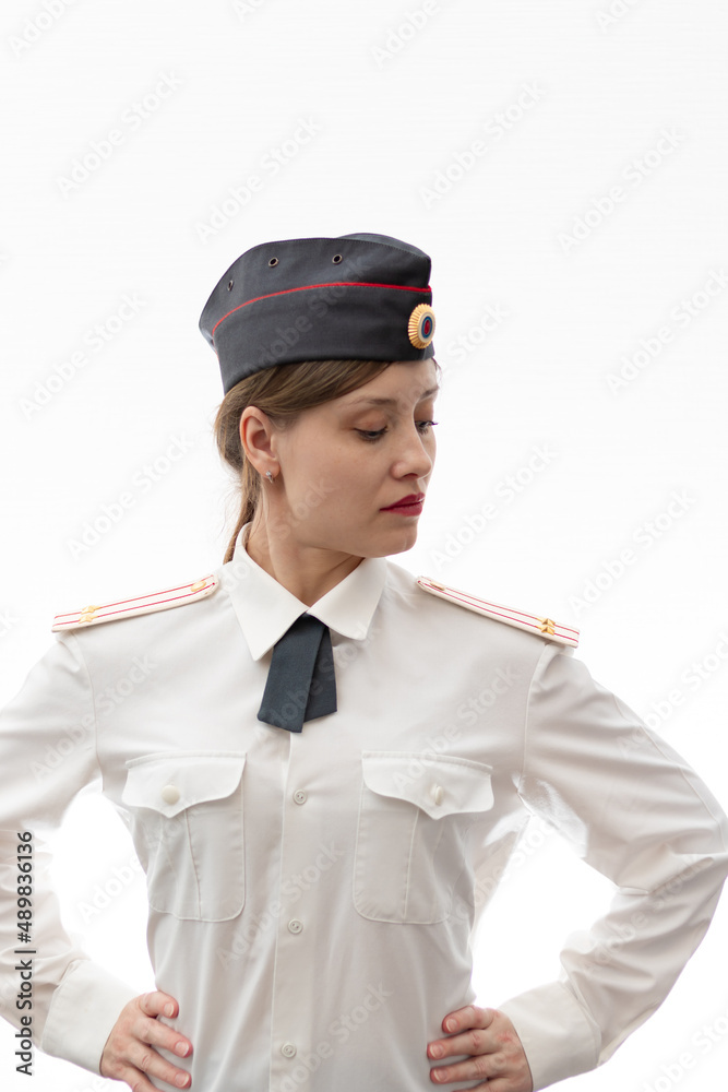 A beautiful young female Russian police officer in dress uniform in a cap and shoulder straps of a lieutenant colonel and a white shirt on a white background. Selective focus. Portrait A beautiful young female Russian police officer in dress uniform in a cap and shoulder straps of a lieutenant colonel and a white shirt on a white background. Selective focus. Portrait