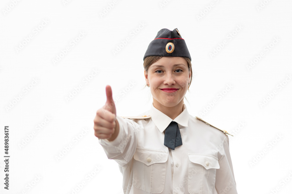 Beautiful young female Russian police officer in dress uniform shows hand signs perfectly and smiles on a white background. Selective focus. Portrait Beautiful young female Russian police officer in dress uniform shows hand signs perfectly and smiles on a white background. Selective focus. Portrait