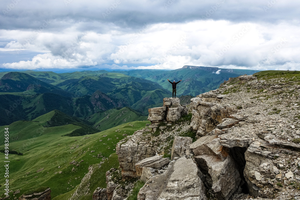 A man on the background of the mountains and the Bermamyt plateau in Russia. June 2021
