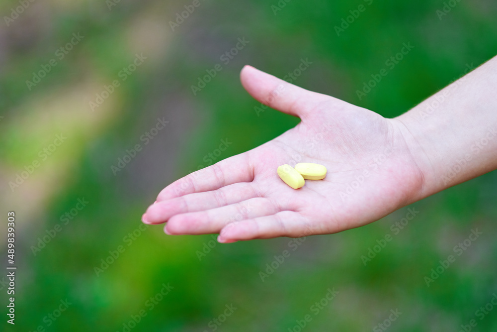 hand holding daily supplements, vitamins or medication on green background hand holding daily supplements, vitamins or medication on green background