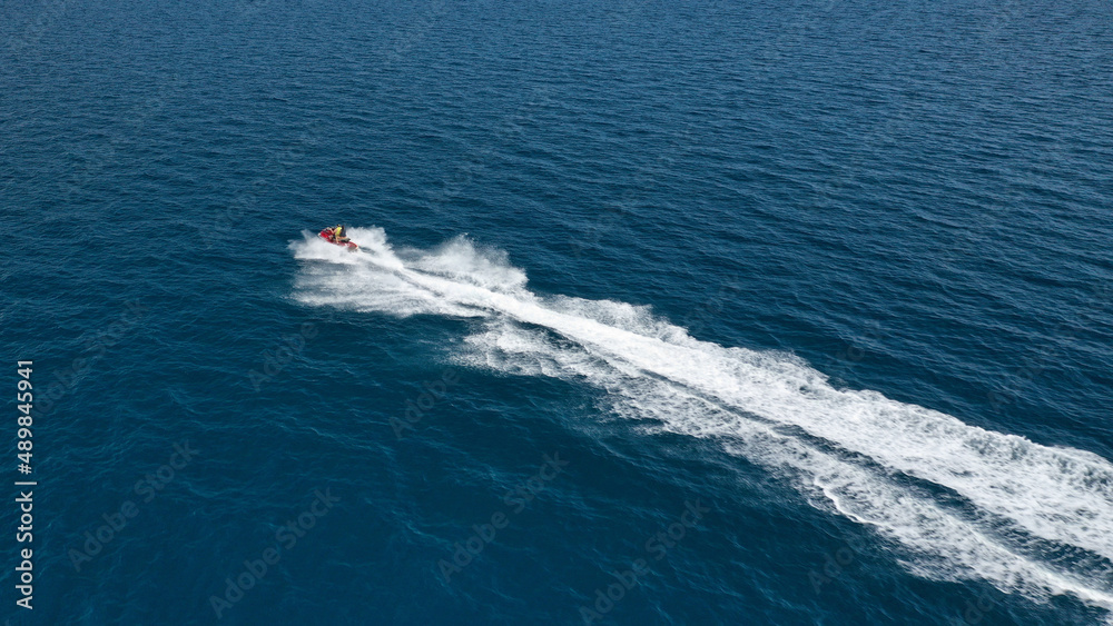 Aerial photo of jet ski with couple cruising in high speed in Caribbean tropical crystal clear deep blue waters Aerial photo of jet ski with couple cruising in high speed in Caribbean tropical crystal clear deep blue waters
