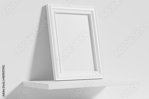 Rectangular photo frame on white shelf leaning at wall diagonal view