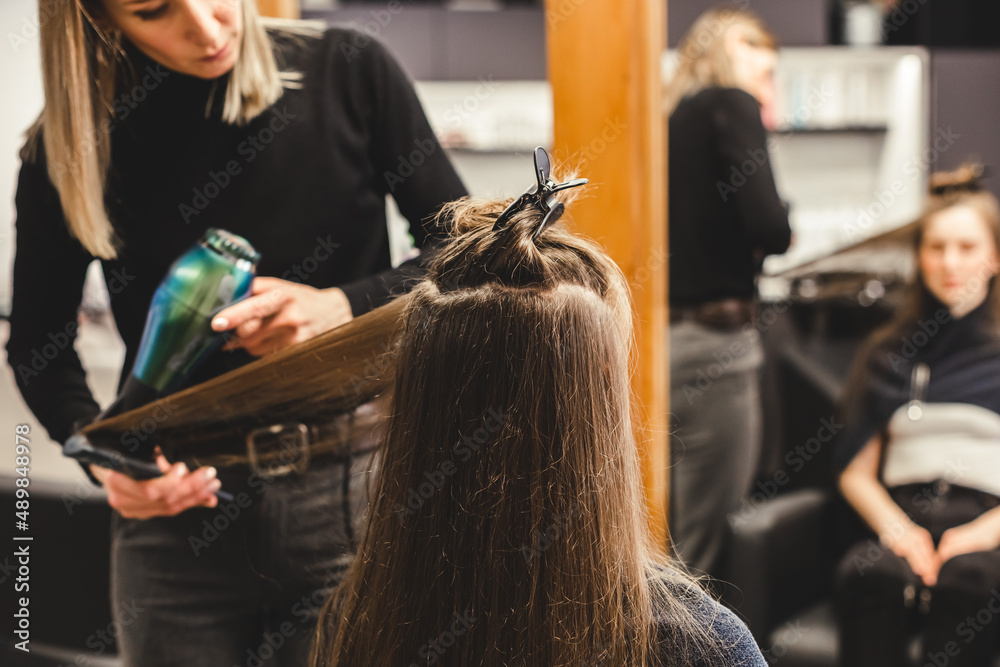 Φωτογραφία Master woman hairdresser dries the girl's hair with a hairdryer after washing in a beauty salon