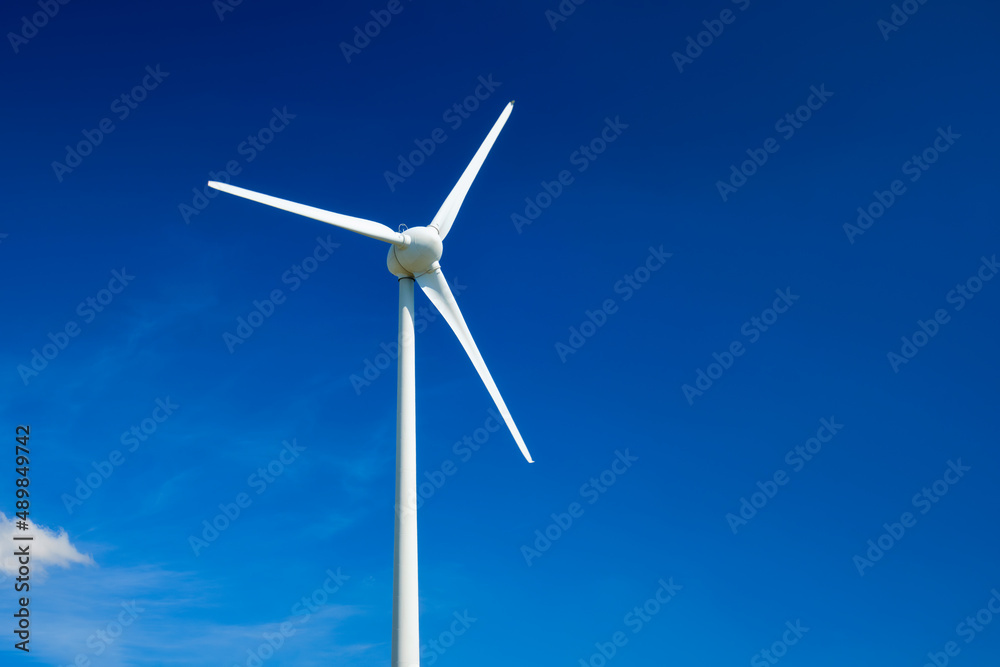 Green renewable alternative energy concept - wind generator turbines generating electricity in blue sky Green renewable alternative energy concept - wind generator turbines generating electricity in blue sky
