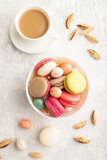Different colors macaroons and chocolate eggs in ceramic bowl, cup of coffee on gray concrete background. top view, close up.