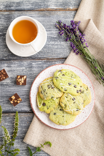 Green cookies with chocolate and mint with cup of green tea on gray wooden background. top view, close up.
