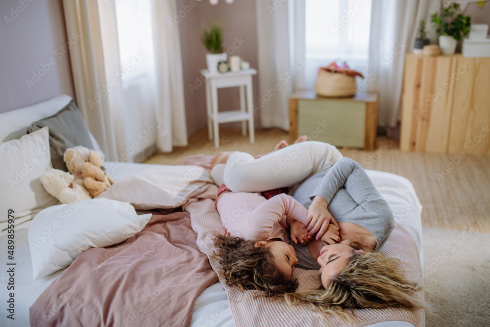 Happy mother with her little daughter lying and looking at each other together on bed at home. Happy mother with her little daughter lying and looking at each other together on bed at home.