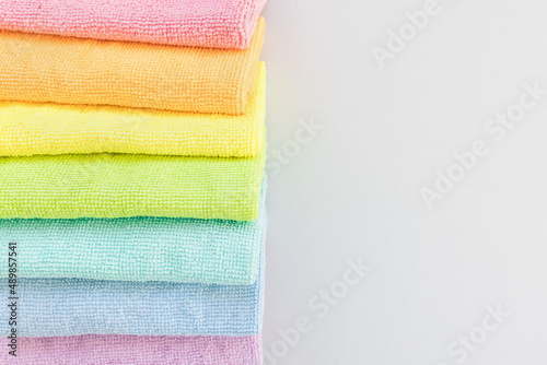 New folded microfiber cloth for cleaning in seven rainbow colors on gray background. Cleaning micro fabric towels for dusting and polishing. Domestic household cleaning service concept. Top view