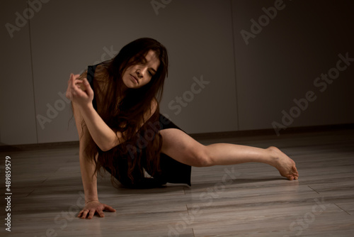 Slender flexible dance performer during a dance practice in modern studio