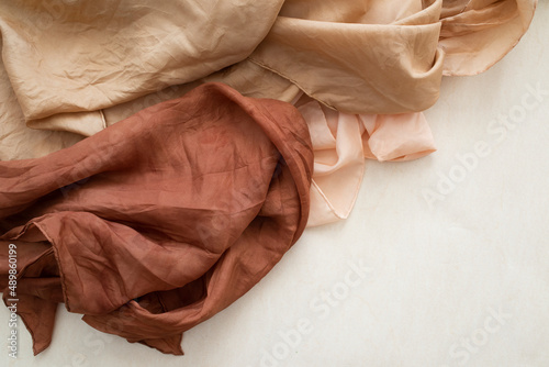 hand dyed clothes in warm natural tones on a bright background - text space -
slow fashion concept 