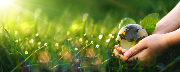 Earth Day.Hand holding crystal earth globe. Environment day, save clean planet, ecology concept.Renewable energy-based green businesses can limit climate change and global warming.