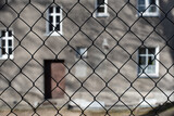 The wire fence against the background of an old tenement house with doors and windows 